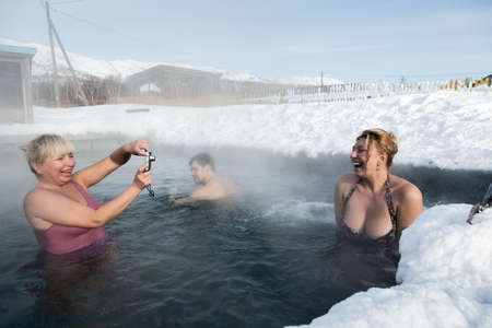 KAMCHATKA PENINSULA, RUSSIA - FEB 02, 2013: Two joyful women photographed while swimming in geothermal spa in hot spring pool in winter. Eurasia, Russian Far East, Kamchatsky Krai, Anavgay Village.のeditorial素材