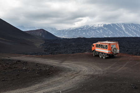 KAMCHATKA PENINSULA, RUSSIA - JUNE 24, 2016: Russian expedition truck KamAZ (6-wheel drive) on mountain road on background of lava fields and volcanoes. Eurasia, Far East, Russia, Kamchatka Region, Klyuchevskaya Group of Volcanoes.のeditorial素材