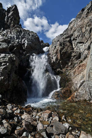 Picturesque view of the waterfall on the mountain river and blue sky with clouds. Far East, Russia, Kamchatka Region.の写真素材