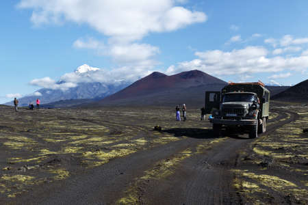 TOLBACHIK VOLCANO, KAMCHATKA PENINSULA, RUSSIA - AUG 27, 2014: Russian extreme off-road expedition truck ZIL-131 (6-wheel drive) on mountain road on background of volcanic cinder cone and beautiful volcano. Kamchatka, Klyuchevskaya Group of Volcanoesのeditorial素材