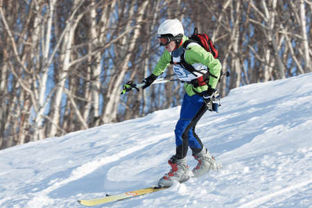 KRASNAYA SOPKA, PETROPAVLOVSK-KAMCHATSKY, KAMCHATKA, RUSSIA - FEB 4, 2012: Ski mountaineer rides skiing on mountain on forest background. Ski-mountaineering competitions - Cup Petropavlovsk City.のeditorial素材