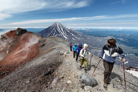 AVACHA VOLCANO, KAMCHATKA PENINSULA, RUSSIAN FAR EAST - AUG 7, 2014: Group of hikers climbing along the edge of summit crater of active Avachinsky Volcano on background of cone of Koryak Volcano.のeditorial素材