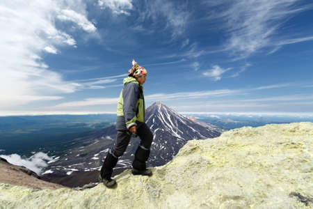 AVACHA VOLCANO, KAMCHATKA PENINSULA, RUSSIAN FAR EAST - AUG 7, 2014: Young women tourists climb to sulfur fumarole field in crater of active Avachinsky Volcano on background of cone of Koryak Volcano.のeditorial素材