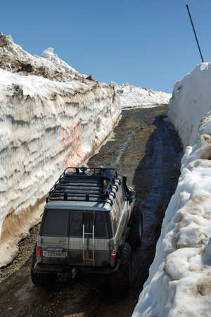 KAMCHATKA PENINSULA, RUSSIAN FAR EAST - JUNE 18, 2017: Japanese off-road cars Toyota Land Cruiser Prado driving on mountain road in snow tunnel surrounded by high snowdrifts on Vilyuchinsky Pass.のeditorial素材