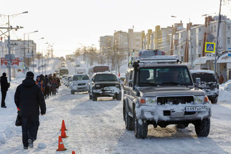 PETROPAVLOVSK CITY, KAMCHATKA PENINSULA, RUSSIA - DEC 27, 2017: Traffic on main road of capital of Kamchatka Region, people walk along the edge of road that is not completely cleared after snowstormのeditorial素材