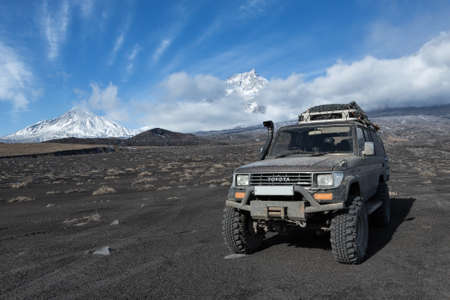 KAMCHATKA PENINSULA, RUSSIA - OCT 1, 2016: Japanese 4wd car Toyota Land Cruiser Prado prepared for long travel and off-road tourism through mountains parked on volcanic slag on background volcanoes.のeditorial素材