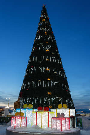 Night view of festive decorated luminous Christmas tree in snowy town Happy New Year.の写真素材