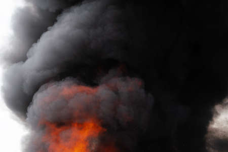 Dangerous flames of strong red fire and motion clouds of black smoke covered sky. Defocus, motion blur from fire and high temperature from flames. Atmospheric and smoke dispersion.の写真素材