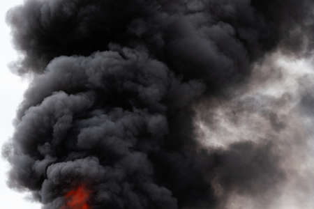 View of black motion clouds of strong fire smoke covered sky. Defocus and motion blur from fire and high temperature from flames. Smoke and atmospheric dispersion.の写真素材