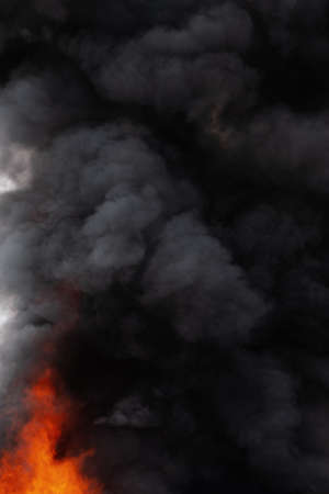 Black motion clouds of strong red fire smoke covered sky. Defocus and motion blur from fire and high temperature from flames. Atmospheric and smoke dispersion.の写真素材