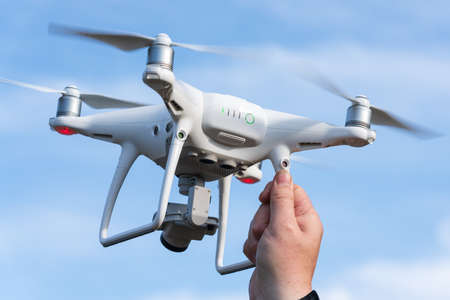 Male hand catches / launches professional drone quad copter DJI Phantom 4 Pro with digital camera 4K...