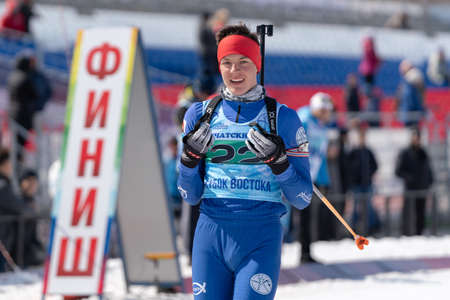 Portrait of sportsman biathlete Sporshev Nikita at finish line after skiing and rifle shooting. Junior biathlon competitions East of Cup. Petropavlovsk, Kamchatka Peninsula, Russia - April 14, 2019.のeditorial素材