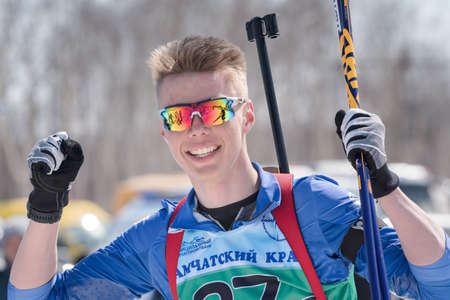 Portrait of happy sportsman biathlete Kozulin Aleksander at finish after skiing, rifle shooting. Junior biathlon competitions East Cup. Petropavlovsk-Kamchatsky City, Kamchatka, Russia - Apr 14, 2019.のeditorial素材