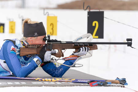 Russian sportswoman biathlete Petrunova Kseniya rifle shooting in prone position. Biathlete in...