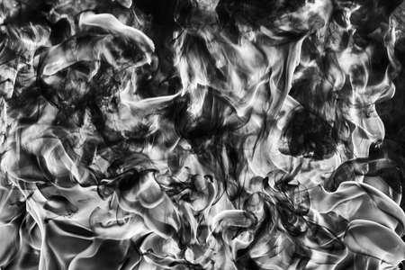 Abstract puffs of natural black smoke and white huge flame of strong fire. Black and white photography, motion blur from fire, high temperature from flames. Dangerous firestorm abstract background.の写真素材
