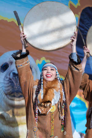 Female dancing with tambourine in national clothing indigenous inhabitants Kamchatka. Concert, celebration Koryak national ritual holiday Hololo Day of Seal. Kamchatka Peninsula, Russia - Nov 4, 2018のeditorial素材