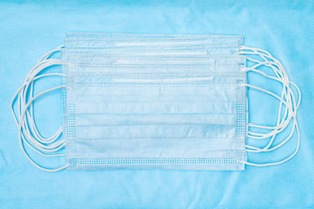 Lot of antibacterial face mask on blue medical background. Concept quarantine, grippe, pandemic outbreak. Antibacterial respiratory bandage for human face covering nose, mouth, respiratory tractの写真素材