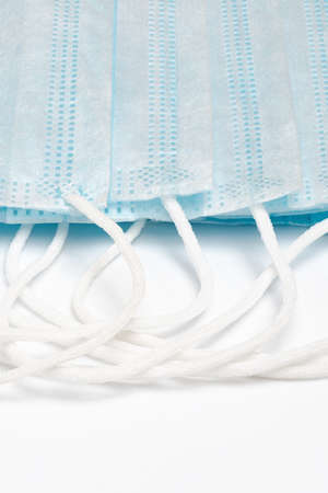 Close-up of blue surgical medical face masks with rubber ear straps on white background. Disposable...