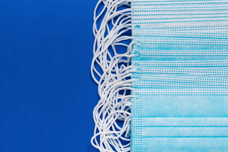 Surgery and medical face masks for coronaviruse on classic blue color background. Close-up of disposable face bandage with rubber ear straps. Copy space, masks effective in protecting from COVID-19の写真素材