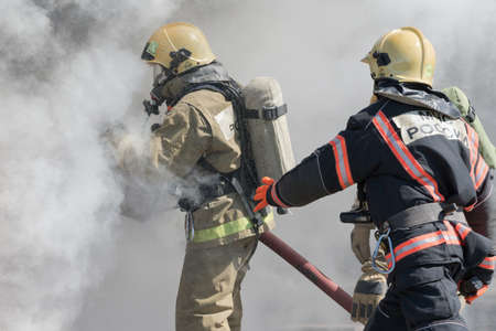 Firefighters extinguishes fire from fire hose, using firefighting water-foam barrel with...