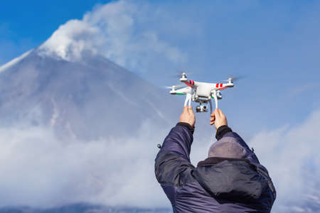 Drone operator catches flying quadcopter UAV on background volcano eruption, mountain peak danger...