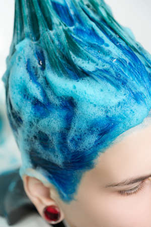 Close-up view of head of beautiful woman with blue hair while shampooing her head in professional beauty salon.の写真素材