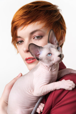 Canadian Sphynx Cat looking away, sitting on shoulder redhead young woman. Selective focus on...