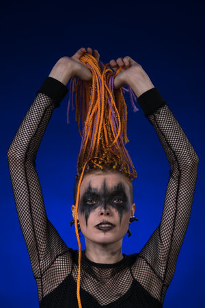 Fine art portrait of beautiful young woman with orange color dreadlocks hairstyle and horror black...