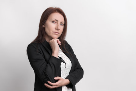 Formal portrait confident businesswoman resting chin on fist and looking at camera. Serious demeanor...