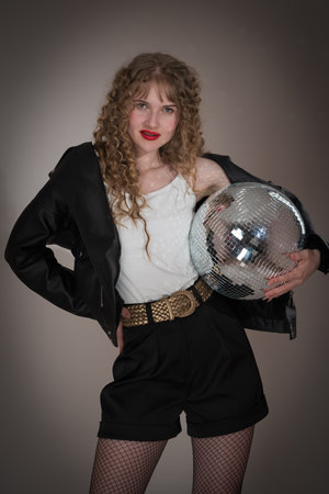 Sensuality young adult woman holding mirror disco ball, looking at camera. Beautiful hipster woman...