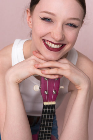 Portrait of young woman musician with ukulele. Beautiful 18 year old woman with big, toothy smile, positive attitude and joyful expression.の写真素材