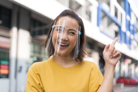 Portrait happy woman wile wearing a face shield for protection from cold and flu and viruses. Young...