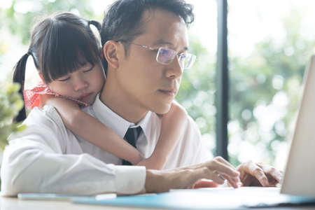 Father working on laptop. businessman working from home and watching child. spending time with kid.の写真素材