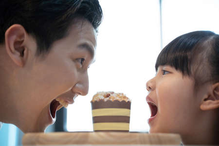 father and daughter looked with open mouths sharing desserts between them. Family concept