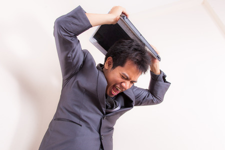 This businessman has lost his temper completely as he stand with his laptop angry and frustrated....