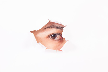 A young woman's eye looking through the cracked wall.の写真素材