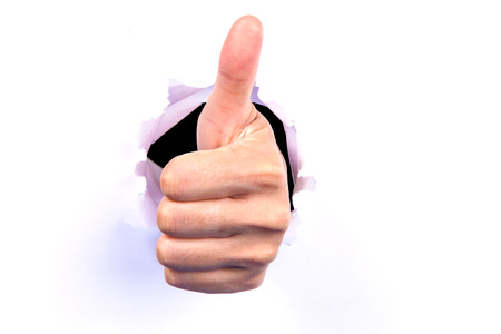 Hand show Thumbs up sign from hole.の写真素材