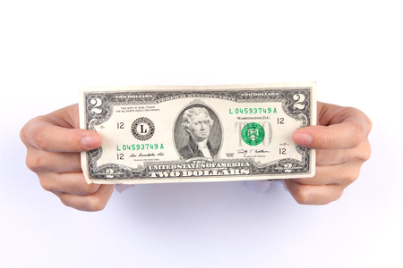 Woman two hand with dollars through a hole in paper isolated on whiteの写真素材