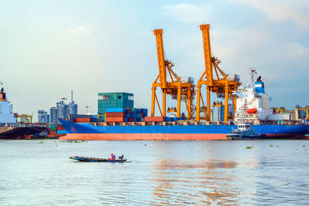 Shipping port, Container Cargo freight ship with working crane loading bridge in shipyard at dusk for Logistic Import Export in Bangkok (With blur trademark, brand, logo.)のeditorial素材