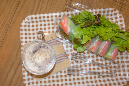 Good for health Asian food, (Kuay Tiew Lui Suan) Fresh spring rolls with assorted vegetables and ice water on the wooden table.の写真素材