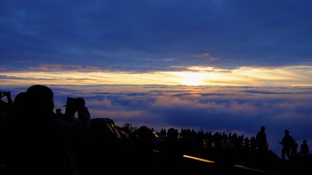 Crowd waiting to see the sunrise in the clouds in the morningの写真素材