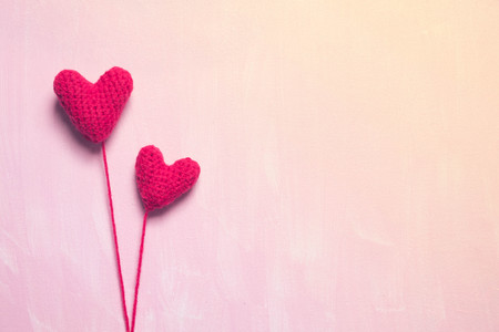 Two red crochet heart on painted pink canvas backgroundの写真素材