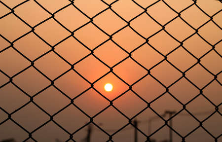 Steel mesh cage and sunsetの写真素材
