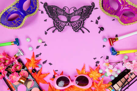 Flat lay top veiw of mask party preparation accessories. cosmetics and brushes on pink backgroundの写真素材