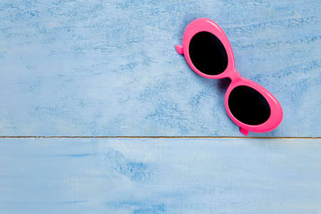 Top view essential pink sunglasses travel items on blue wooden background.Free space for creative design textの写真素材