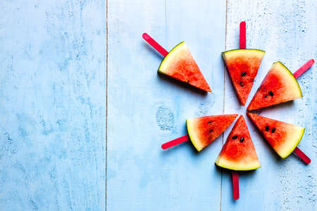 summer concept watermelon slice ice lolly on a blue rustic wood backgroundの写真素材