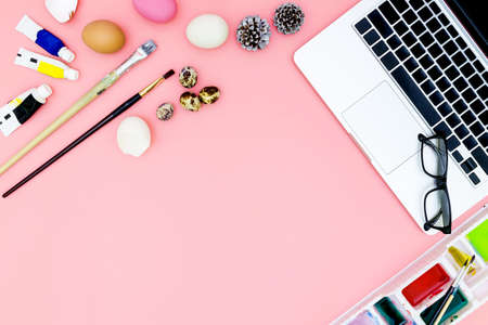 flat lay photo of modern workplace with laptop and eggs, top view laptop background and paint set preparing for Easter on pink background, easter eggsの写真素材