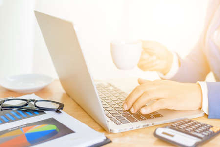 Business accounting plan concept, Working on desktop laptop computer with calculator for making business, business man hand working with laptop computer on wooden desk business investment advisor.の写真素材