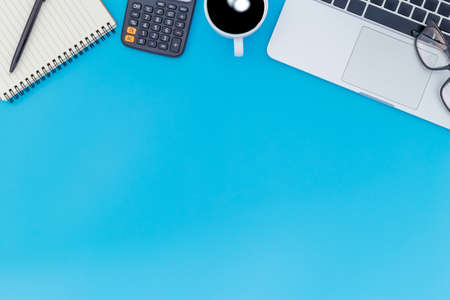 flat lay Office desk table of modern workplace with laptop on blue table, top view laptop background and copy space on black background, blue desk office with laptop, smartphone and other work supplies with mouse.の写真素材