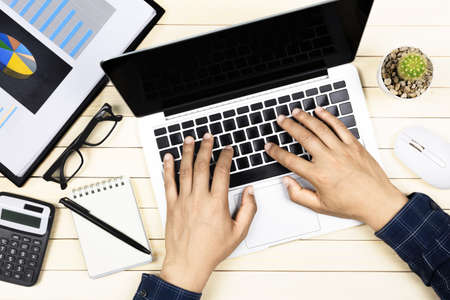 businessman working with modern workplace with laptop on wood table, Man hand on laptop keyboard for work from home, Overhead view of businessman working  in officeの写真素材